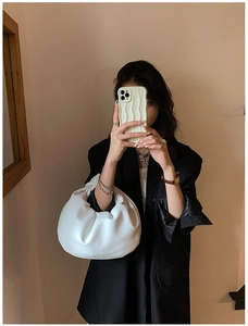 Minimalist white cloud handbag with soft leather texture held by model in black blazer