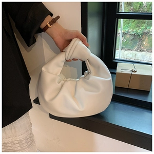 Detail of white pleated cloud bag showing the knotted handle and soft leather texture