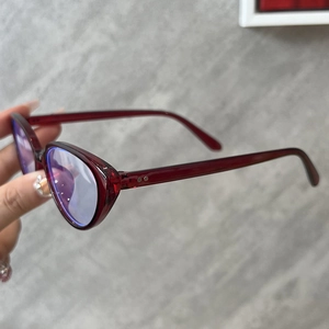 Macro shot of wine red cat eye glasses with anti-blue light coating and metal rivet detail