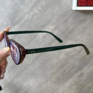 Detail of cat-eye frames with dark green tortoiseshell pattern and blue light lenses