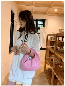 Close-up of pink ruched hobo bag with knotted handle detail and soft leather texture