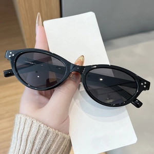 Detailed shot of retro oval sunglasses featuring silver rivet accents on black frames
