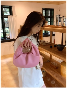 Detailed view of pink knotted cloud bag handle with elegant pleated faux leather texture