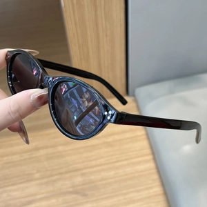 Close-up of retro oval sunglasses with black frames and triple metal rivet details