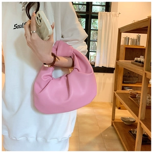 Detail of pink pleated dumpling handbag with knotted handle and soft leather texture