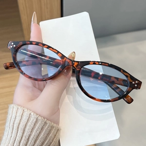 Detail view of retro oval sunglasses with tortoiseshell texture and triple metal rivets