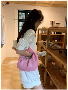 Close-up of pink cloud bag with soft pleats and knotted handle on person