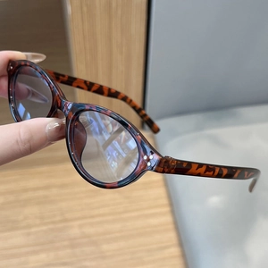 Detail of tortoise shell oval sunglasses featuring light gray lenses and metal accents