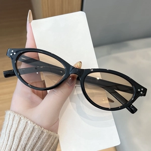 Close-up of black oval sunglasses with amber lenses and silver triple-rivet design