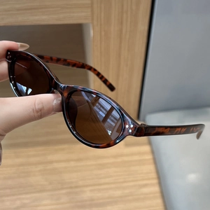 Detail of tortoise shell oval sunglasses with brown lenses and triple metal rivet accents