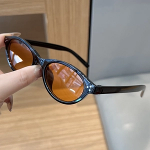 Close-up of retro oval sunglasses with thick black frames and bright orange lenses