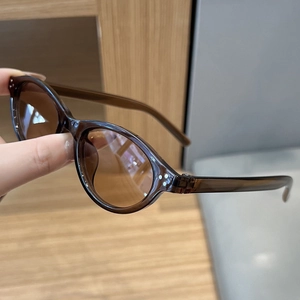 Detail view of retro oval sunglasses with brown transparent frame and silver studs
