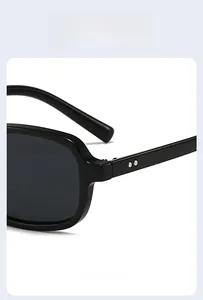 Close-up of black square sunglasses featuring silver metal rivet details on the frame