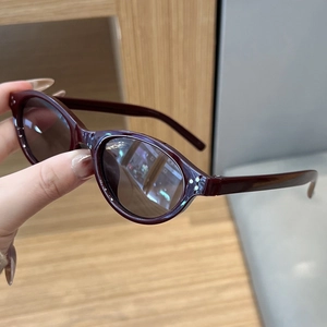 Detailed view of burgundy oval sunglasses frame featuring triple metal rivet accents