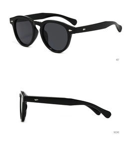 Detail view of round black sunglasses with silver arrow rivet accents and dark lenses