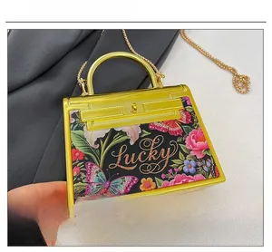 Detail of floral butterfly print on acrylic mini bag with lucky lettering gold frame