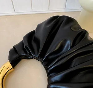 Detailaufnahme der schwarzen Cloud-Tasche mit Lederfalten und goldenem Metallringgriff