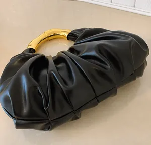Detailansicht der schwarzen Raffungen und des glänzenden goldenen Metallgriffs der Tasche