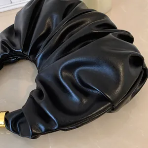 Makroaufnahme der schwarzen Cloud-Bag mit weicher Ledertextur und goldenen Metallteilen