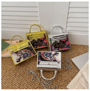 Detail of mini acrylic Kelly bags with gold chain straps and artistic horse prints