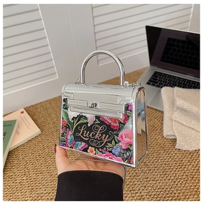 Detailed view of silver mirror acrylic bag with floral butterfly print and Lucky text