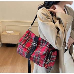 Detail of red plaid tote bag with black leather strap and silver eyelet hardware