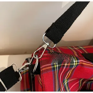 Detail of red plaid tote bag with polished silver metal lobster clasp and black strap