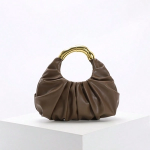 Detailansicht braune Rafftasche mit antikgoldenem Metallgriff im Bambus-Design