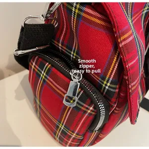 Detail of red plaid canvas tote featuring smooth silver zipper and durable strap hook