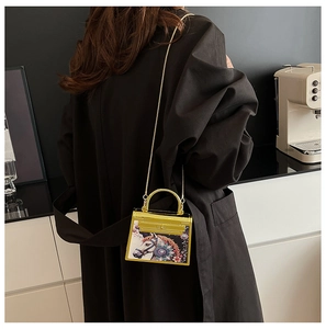 Detailed view of yellow mini acrylic Kelly bag with horse print and gold chain strap