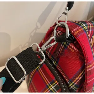 Detail of red plaid tote bag featuring adjustable black nylon strap and silver metal buckle
