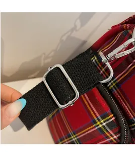 Detail of red plaid tote bag with adjustable black woven shoulder strap and metal buckle