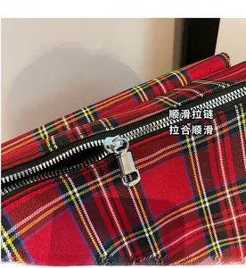 Close-up of smooth silver metal zipper on a red tartan plaid tote bag details