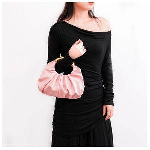 Detail der rosa gerafften Wolken-Tasche mit goldenem Metallgriff am schwarzen Kleid-Modell