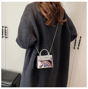 Detailed view of mini silver acrylic bag with colorful horse and flower print on model