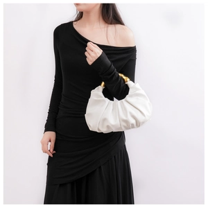 Detail der weißen Cloud-Bag mit goldenem Metallgriff auf einem schwarzen Kleid
