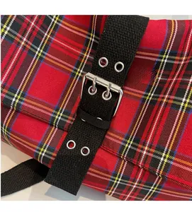Detail of red and black plaid fabric tote bag with metal eyelets and silver buckle strap
