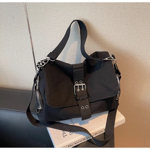 Close-up of black canvas messenger bag featuring dual buckle straps and metallic side zippers