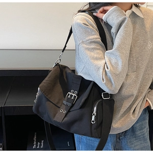 Detail of black canvas messenger bag with double metal buckles and adjustable strap