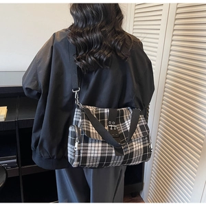 Detail of black and white checkered crossbody bag featuring silver hardware and strap