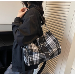 Detail of black and white plaid messenger bag featuring side zipper and metal buckle