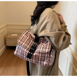 Macro detail of pink plaid canvas crossbody bag featuring metal buckles and side zip pocket