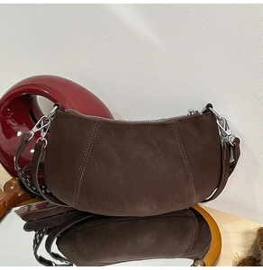 Macro view showing the matte suede texture and curved decorative stitching on the brown bag