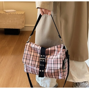 Pink and black checkered crossbody bag with adjustable wide strap shown in street style