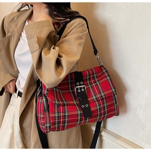 Detail of red tartan messenger bag featuring a metal buckle strap and side zipper pocket