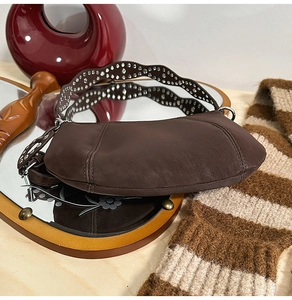 Detail view of dark brown leather handbag with silver studded wavy shoulder strap