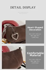 Detail view of dark brown textured leather bag with heart charm and rivet hardware