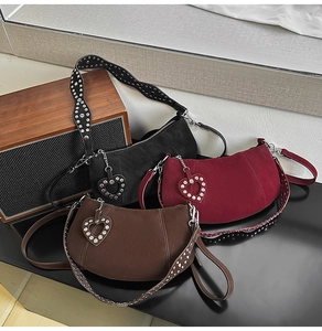 Close-up of suede dumpling bags in black, burgundy, and brown with studded straps