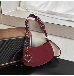 Close-up of wine red crescent bag featuring studded straps and heart-shaped charm detail