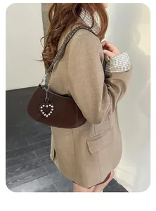 Detail of dark brown matte leather bag with heart charm and rivet strap details